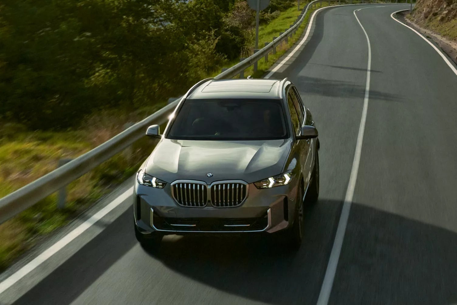 A gray BMW X5 driving down the road