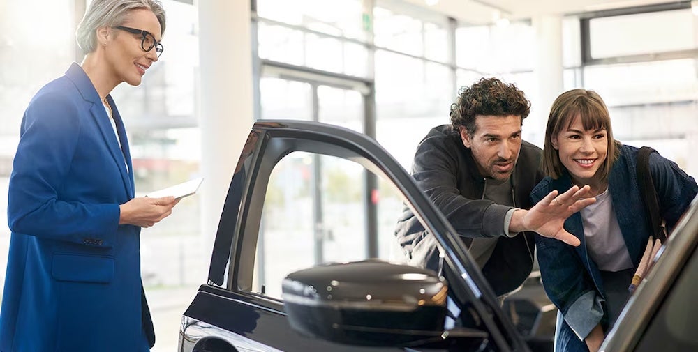 A car dealer and customers examining a BMW vehicle